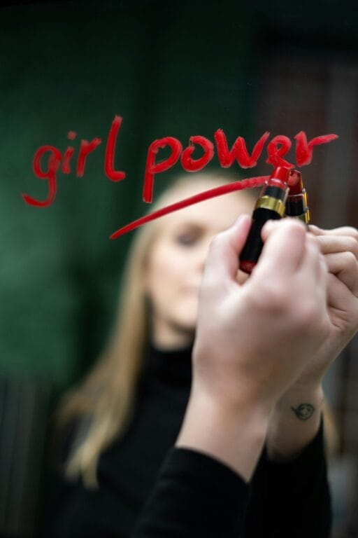 8 Μαρτίου Γιορτή Γυναίκας: Μήνυμα 'Girl Power' γραμμένο με κραγιόν σε καθρέφτη, συμβολίζοντας τη γυναικεία ενδυνάμωση.